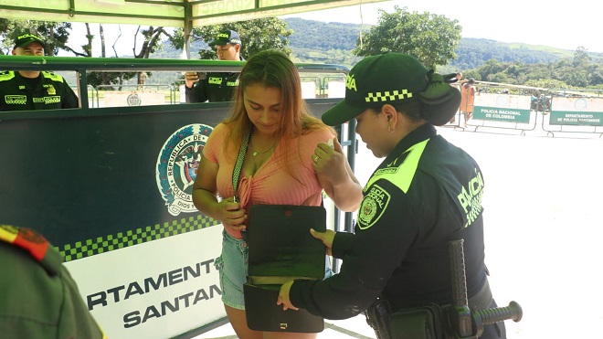 Policía femenina realizando un registro a personas en el ingreso al puesto de votación.