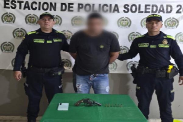 Dos polic&iacute;as, un capturado y arma de fuego encima de la mesa