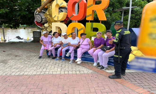 un uniformado brindando recomendaciones a siete ciudadanas en el parque principal de la ciudad de Montería