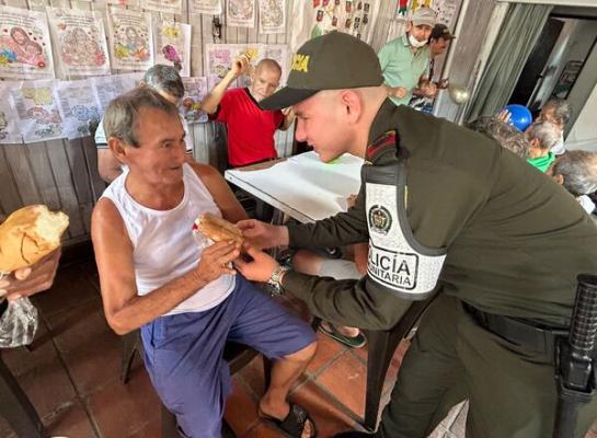Uniformado de la policía comunitaria comparte alimento con los adultos mayores.