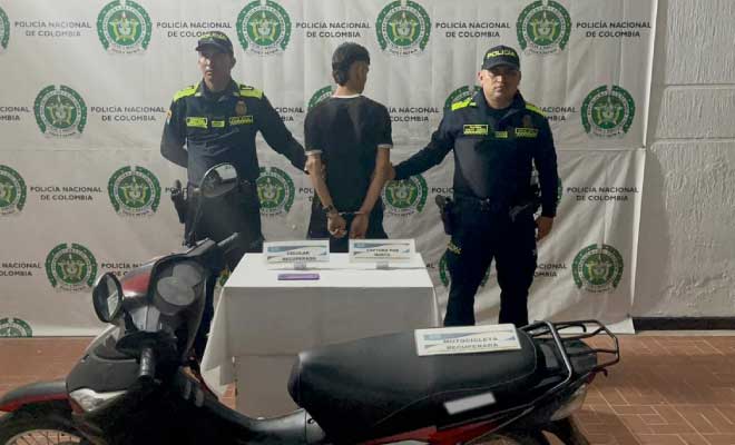Hombre capturado en medio de dos Polic&iacute;as, en frente motocicleta recuperada