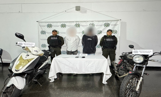 Dentro de un sal&oacute;n, la Polic&iacute;a Nacional presenta a dos hombres con sus rostros difuminados como presuntos responsables de un caso de extorsi&oacute;n. En el lugar tambi&eacute;n se muestran dos motocicletas y varios tel&eacute;fonos celulares que fueron incautados durante el operativo
