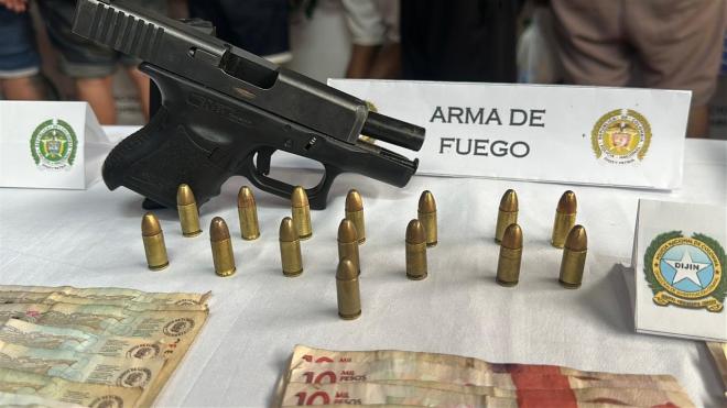 Elementos incautados sobre una mesa, un arma de fuego y dinero en efectivo