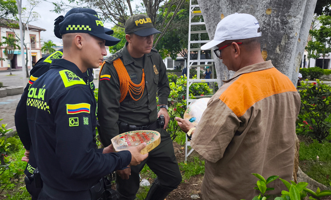 Un ciudadano y dos Policías observando una placa de madera tallada 