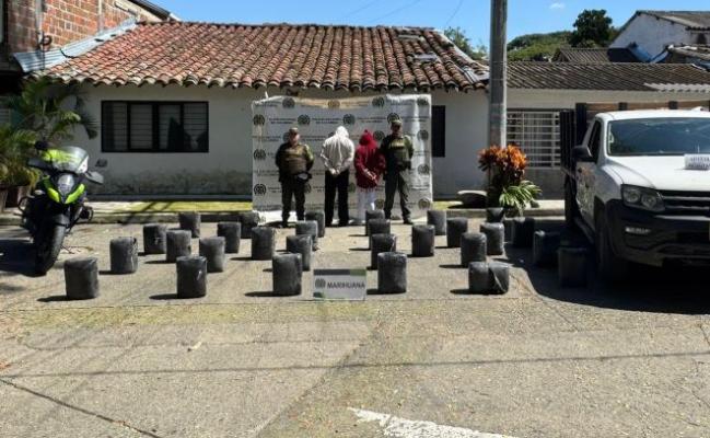 dos policías al lado de dos hombres capturados con estupefacientes