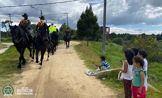 Policías carabineros montados a caballo- niños observándolos 