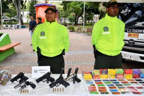 Dos polic&iacute;as encima de una mesa material incautado